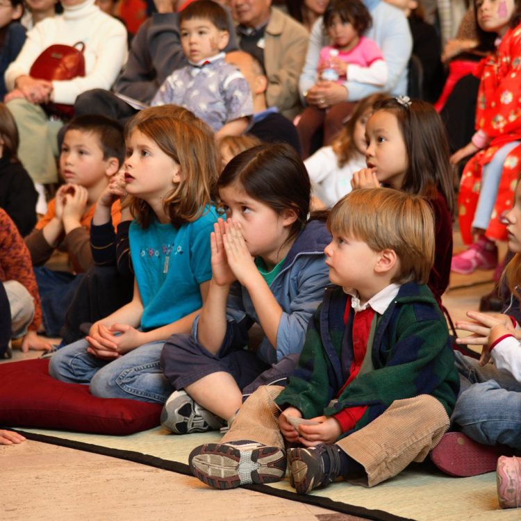 A group of small children sitting on the ground.
