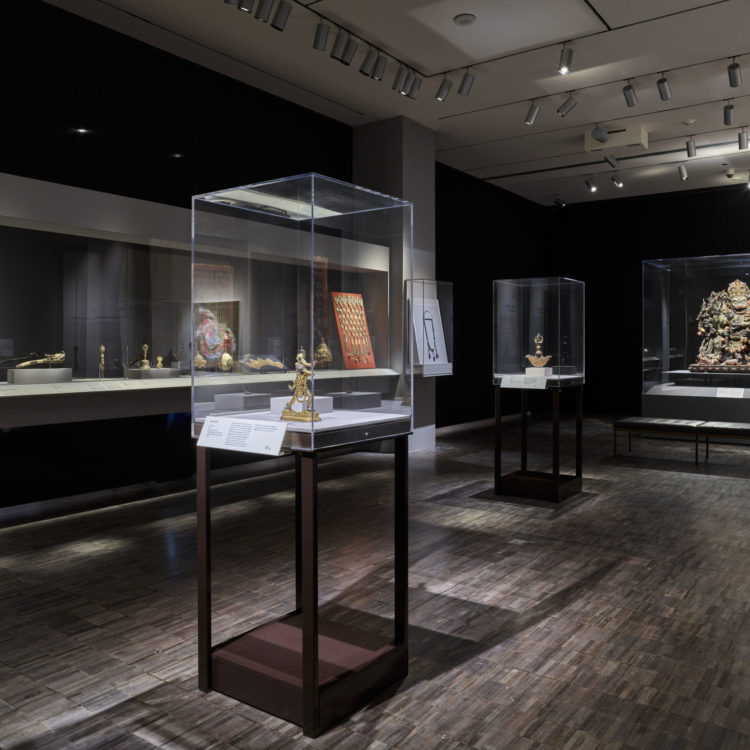 A dimly lit gallery with Tibetan Buddhist artwork.