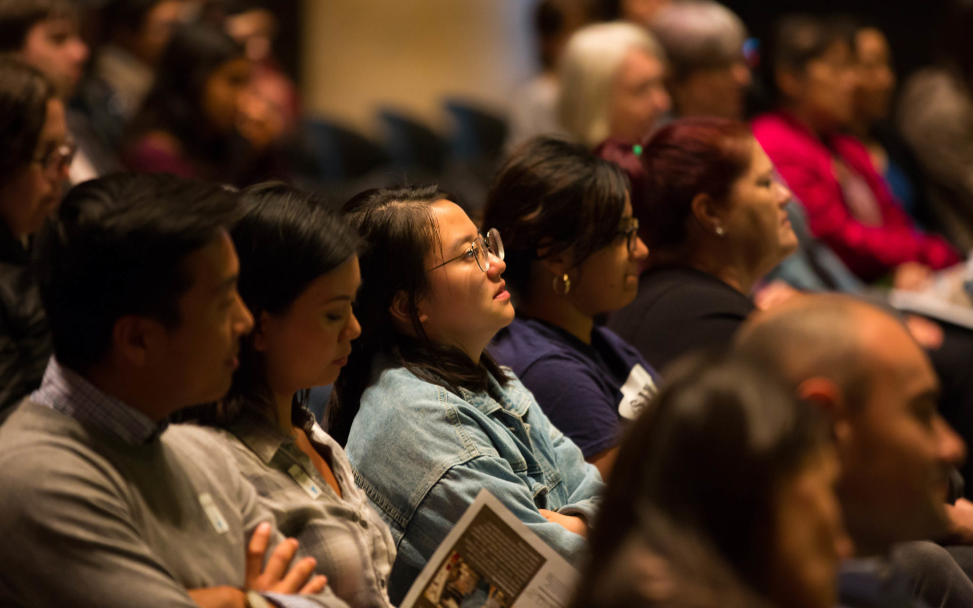 A row of visitors in the audience of a public program.