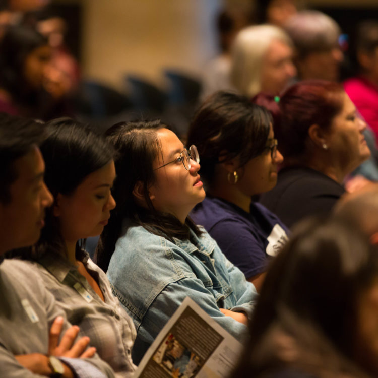 A row of visitors in the audience of a public program.