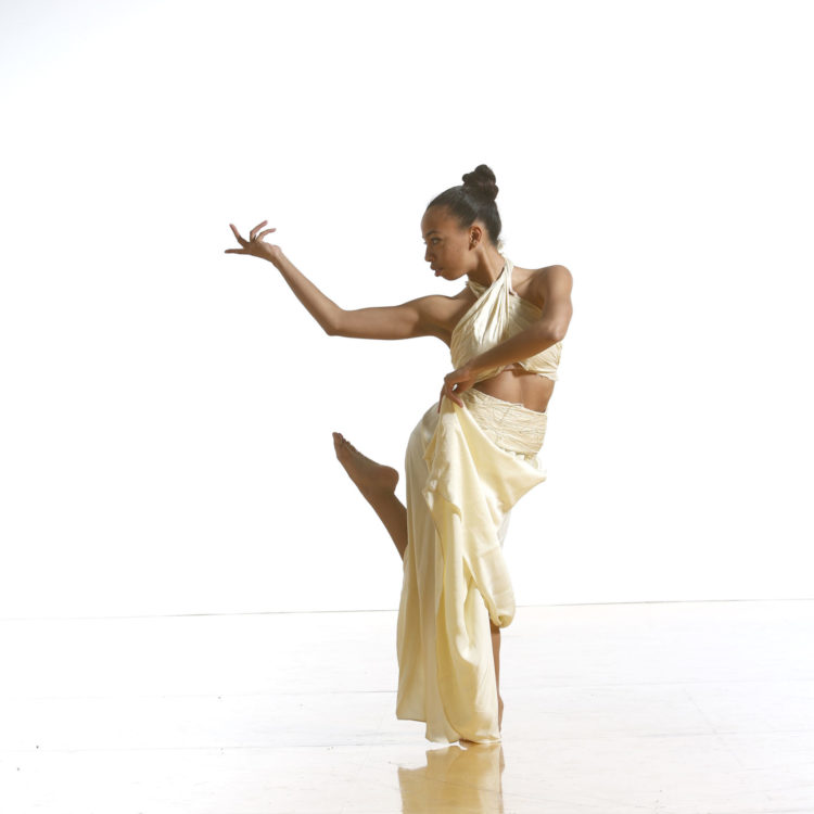 A dancer wearing a white skirt and halter top.