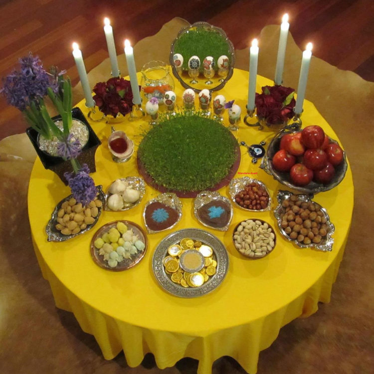 A tabled set with many dishes and candles on a yellow tablecloth.