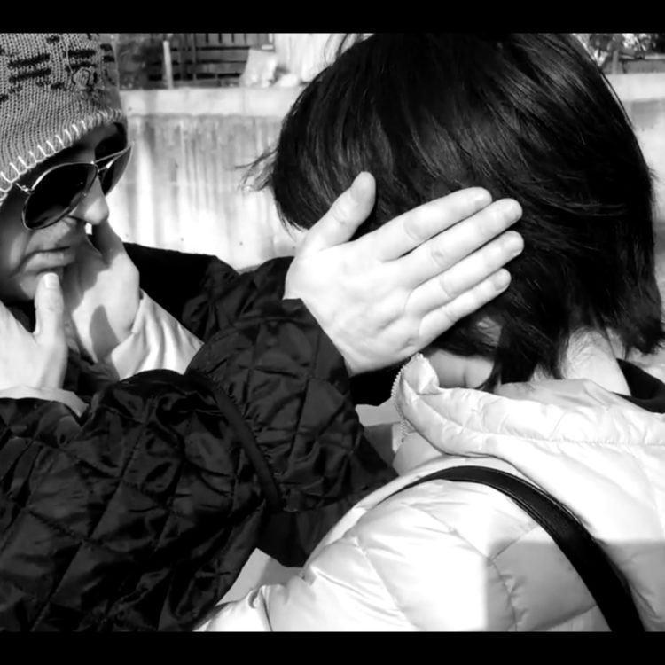 Black and white photograph of two people with their hands on the sides of one another