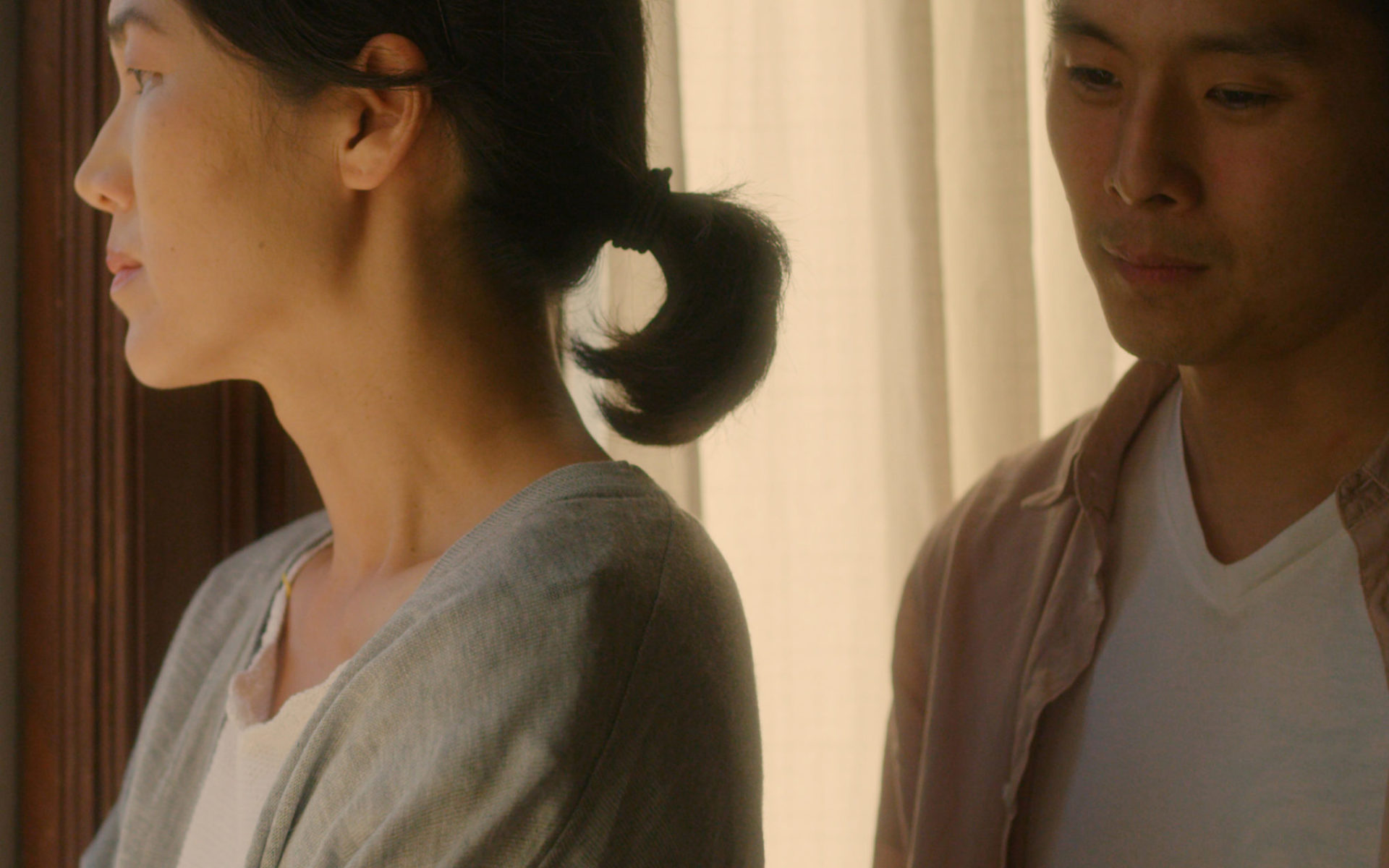 A man stands behind a woman who has her arms folded.