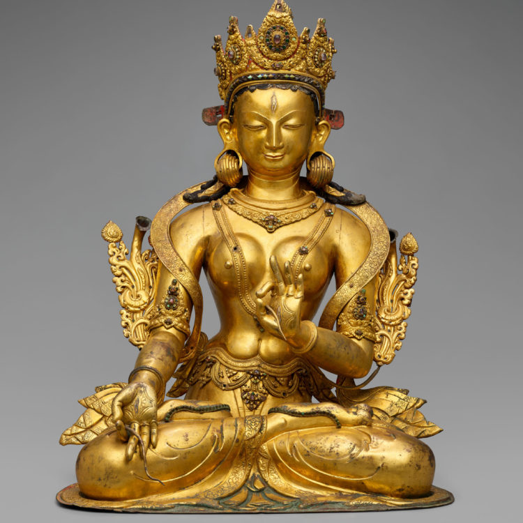 Gilded, crowned and bejeweled female figure, seated in lotus position.