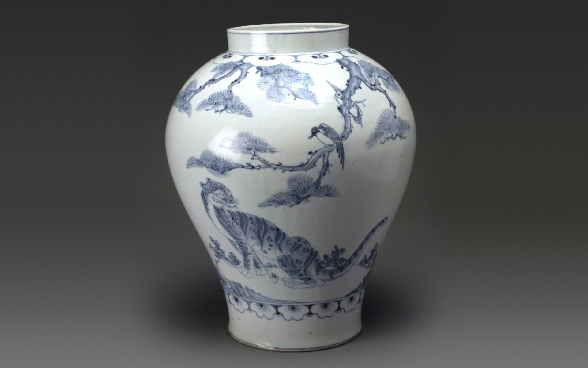 A wide-mouthed white porcelain jar with a tiger and magpie painted in blue.