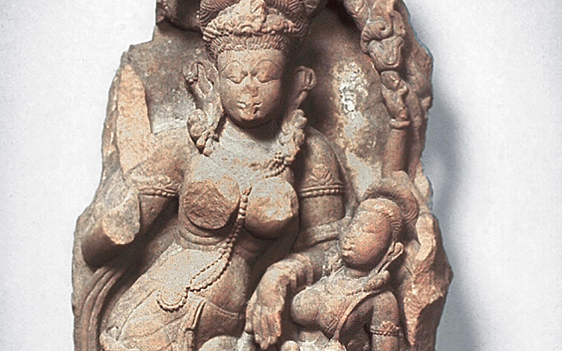A 31-inch tall sculpture of a bejeweled and curvaceous standing female figure with a shorter companion carved in brown stone.