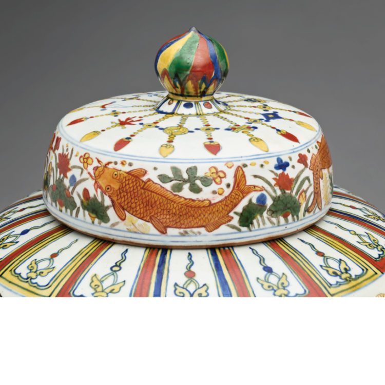 Close-up of a jar lid painted in red, blue, yellow, and green patterns with fish.