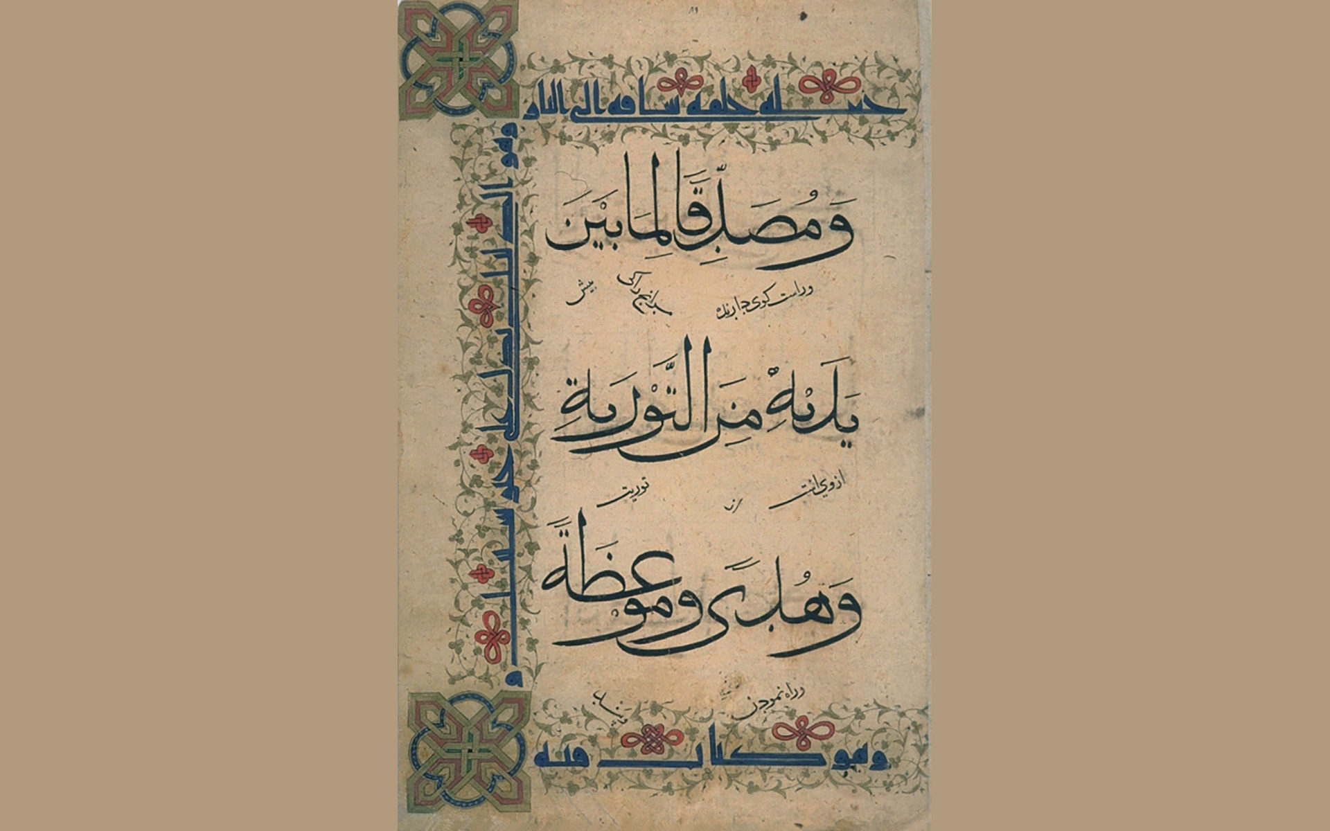 A manuscript page with three horizontal lines of Arabic calligraphy in black on cream-colored paper embellished with a pale green foliated border punctuated by red knots on the top, left, and bottom edge. Inside this border in another style of calligraphy in blue ink is more Arabic writing.